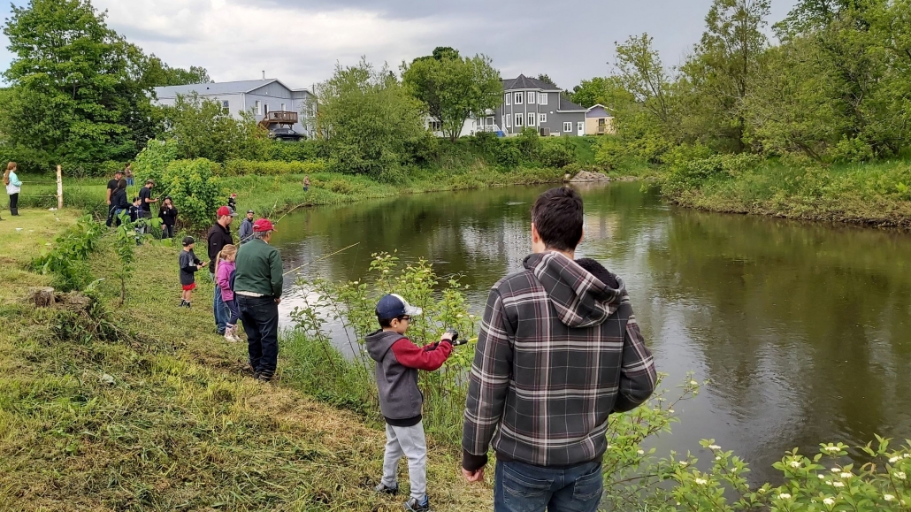 Vue sur des enfants qui apprennent à pêcher au bord d'une rivière.