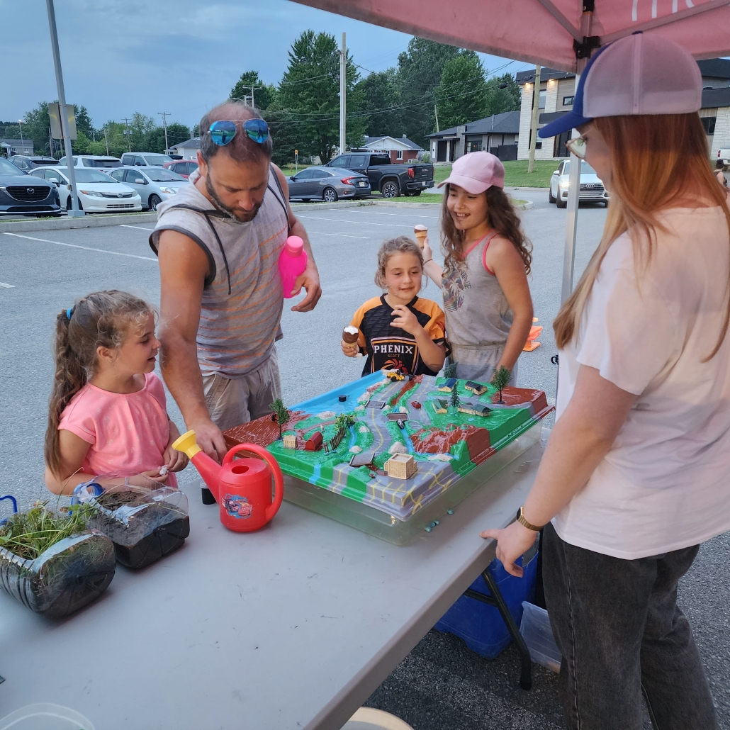 Photo d'une famille devant une maquette educative sur la notion de bassin versant.