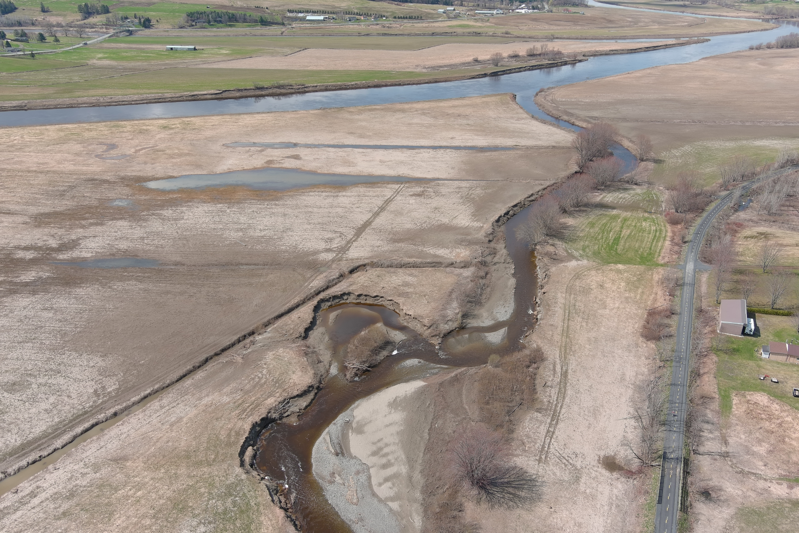 vue aerienne en milieu agricole d'une rivière qui se jette dans la rivière Chaudière en arriere plan.
